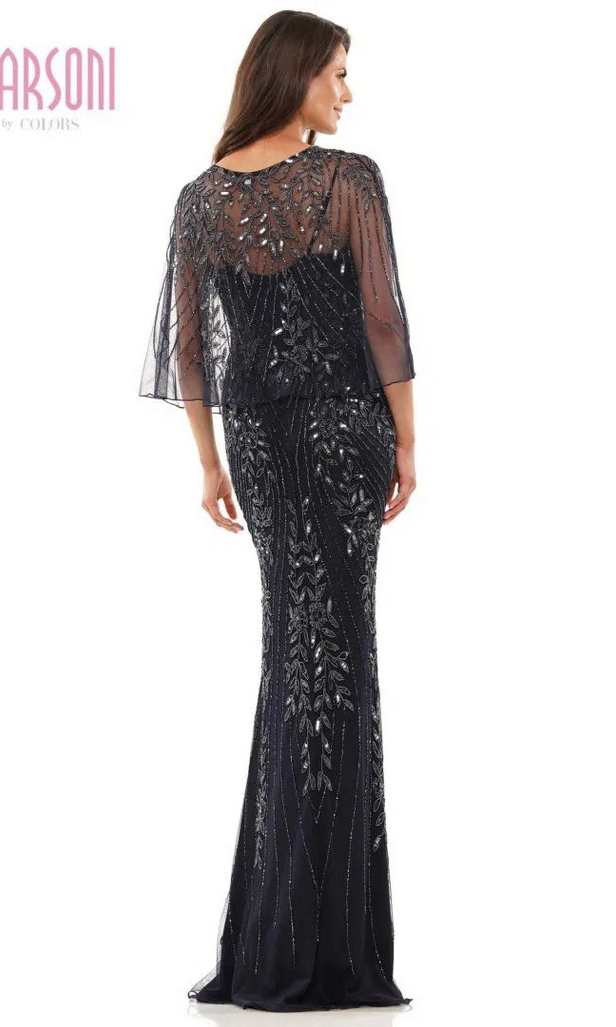Wearing the Marsoni MV1201, a long black formal dress with a sleeveless design, silver beaded details, and a sheer embellished overlay, the woman stands with her back to the camera.